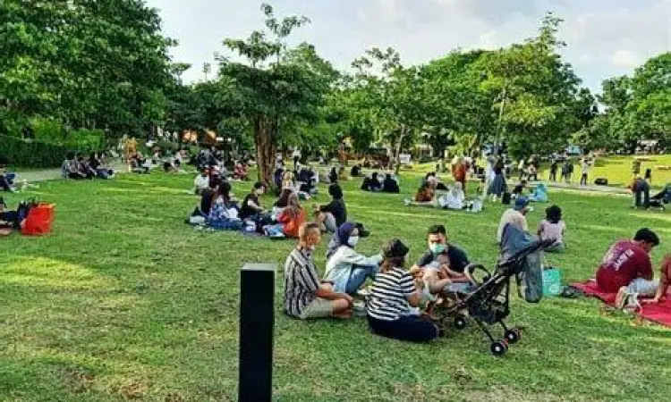 Keluarga sedang piknik di rumput Hutan Kota GBK