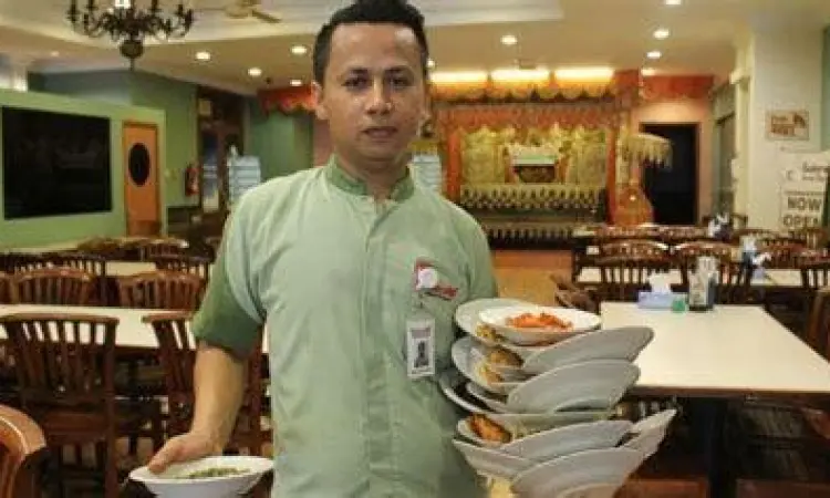 Pelayan membawa banyak piring nasi padang